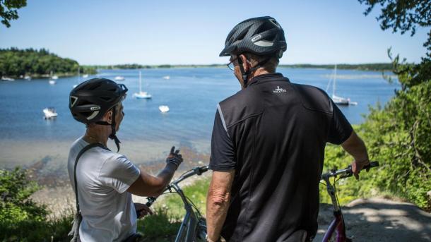 Two cyclists enjoy the view of the Roskilde Fjord in the Skjoldungernes Land National Park in Denmark