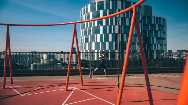 A lady running at the rooftop playground Konditaget Lüders in Nordhavn, Copenhagen, Denmark