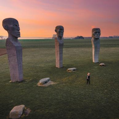 Person looking at stone sculptures Dodekalitten during sunset on Lolland-Falster, Denmark