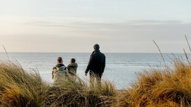 Familie kijkt naar de zee bij Blåvand strand, West-Jutland