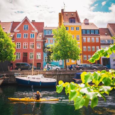 Woman kayaking past coloured houses in Christianshavn