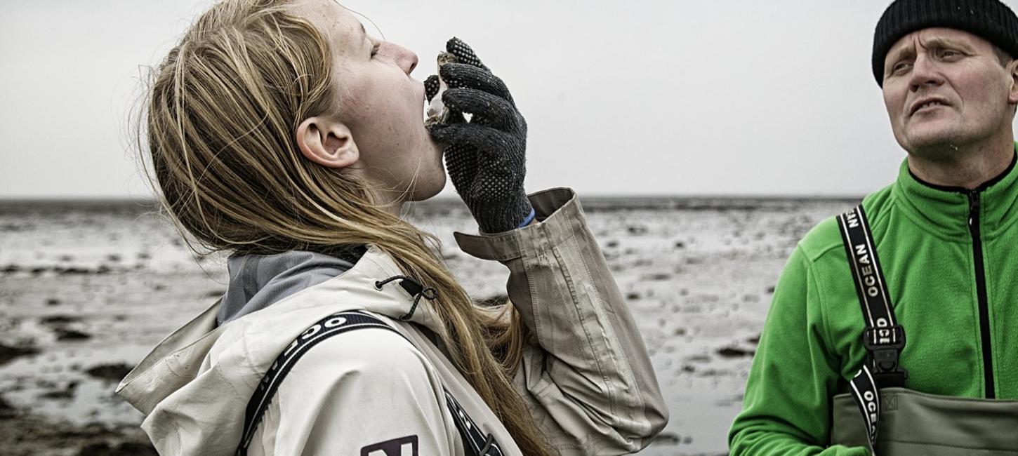 An girl eats a fresh oyster at the Wadden Sea National Park in Denmark