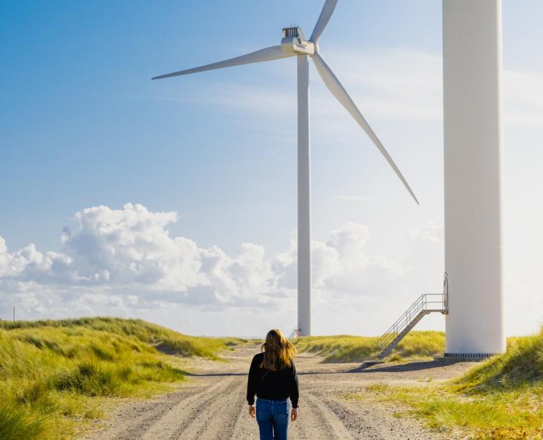 Woman walking towards a windmill at Hvide Sande, Jutland